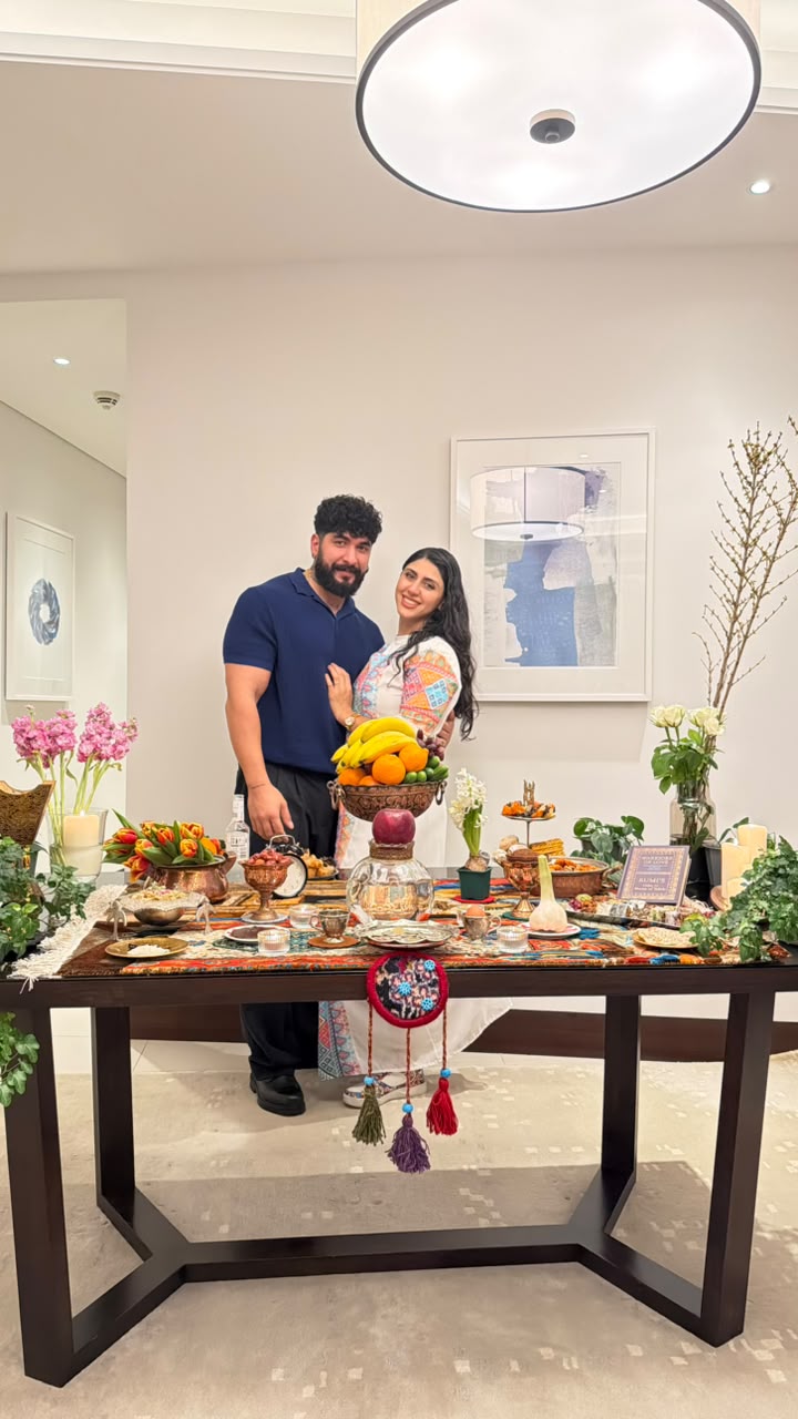 Sadaf and Arash beside a Nowruz haft-sin table